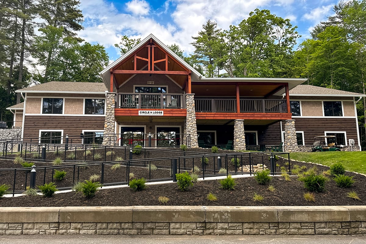Exterior of Double H Ranch's new residential lodge with stone pillars, sidewalk, and landscaping.