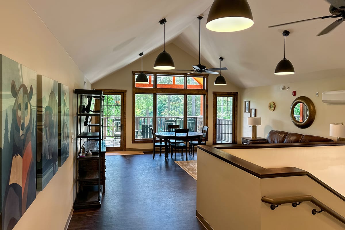 Living room with hardwood floors, wooden furniture, and large windows.