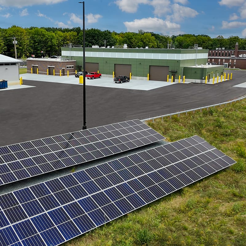 Two rows of solar panels located in a field behind a new maintenance facility built for the New York Army National Guard's 42nd Infantry Division.