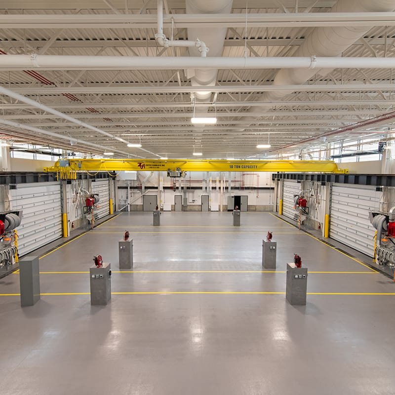 Vehicle maintenance shop with six garage bays, individual workstations, and a yellow single girder crane.