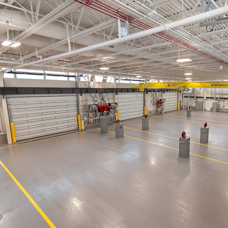 Vehicle maintenance shop with six garage bays, individual workstations, and a yellow single girder crane.
