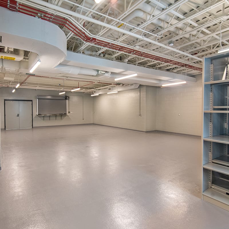 Storage room with white concrete walls, gray flooring and white ceiling located in the New York Army National Guard's new maintenance facility.