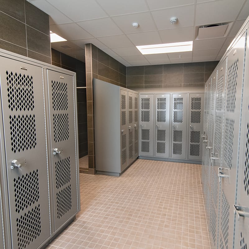 Locker room with gray lockers, orange and brown tiles, and white ceiling tiles located in the New York Army National Guard's new maintenance facility.