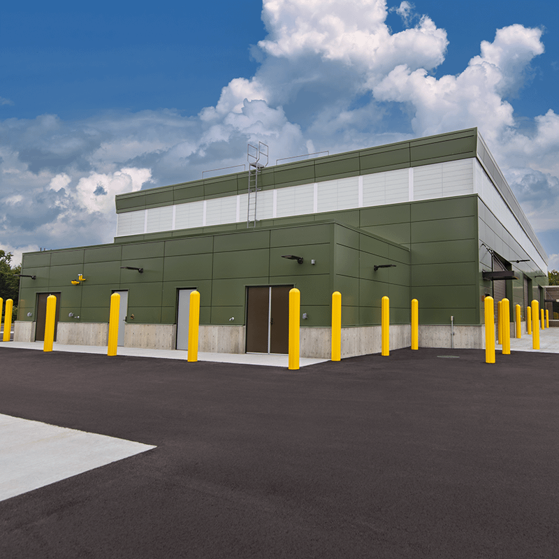 Maintenance shop with six garage bays, a green insulated metal panel exterior and large parking lot.